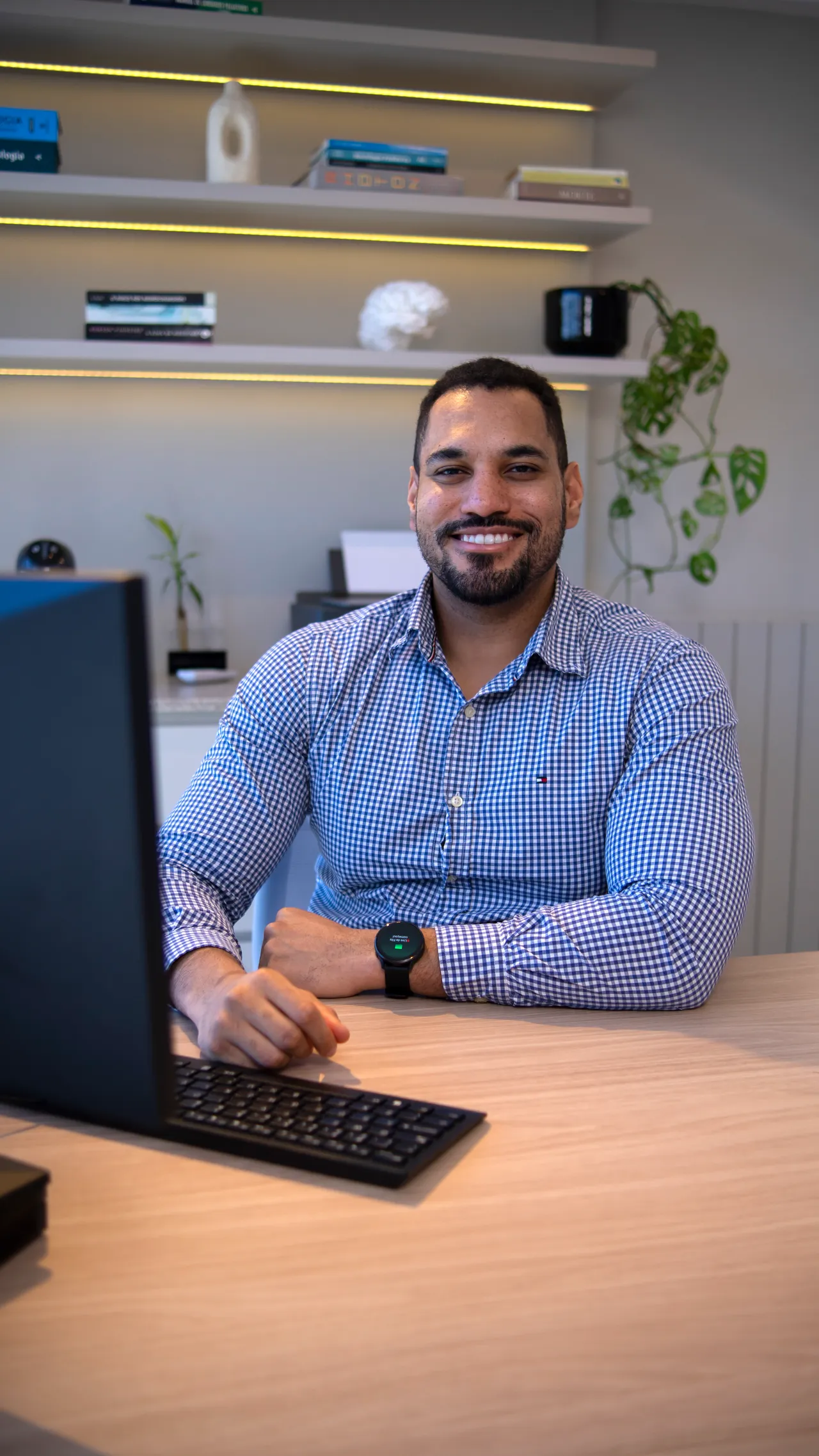 Consultório do Dr. Elson, com estante iluminada, mesa e computador